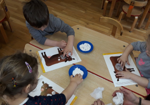 dzieci malują łaty białą farbą